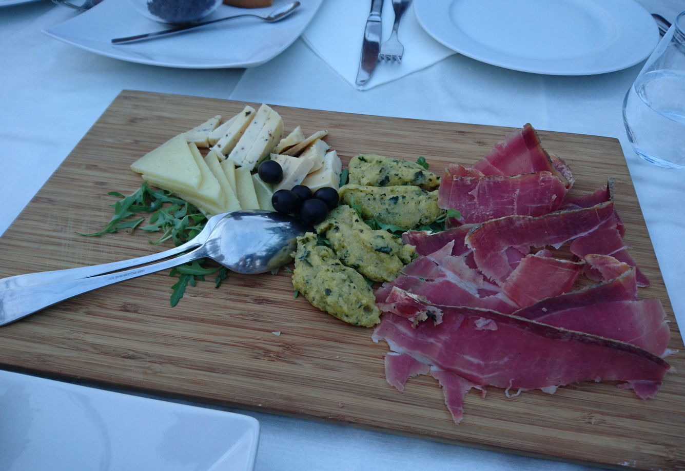 Slicing prosciutto and cheese on a wooden board Prosciutto at Vodnjanka cafe