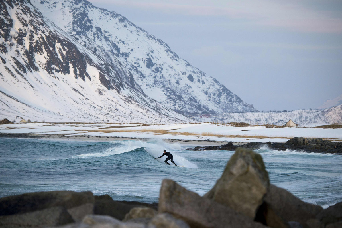 Extreme surfer on a board in the sea in Lofoten Islands Photo: Surfing in Norway