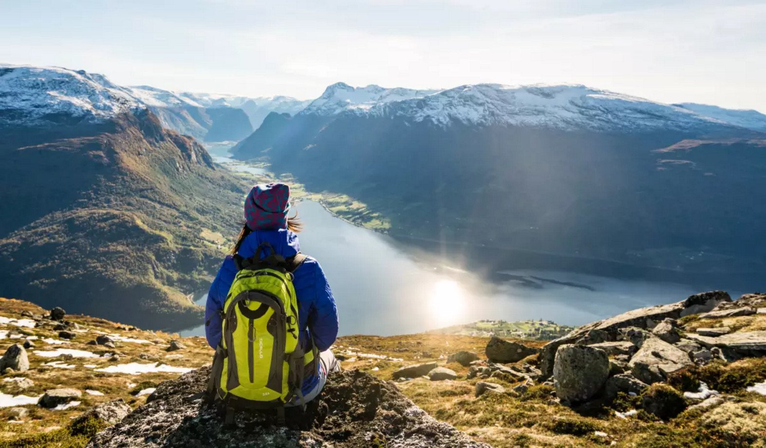 A girl is sitting on the edge of a cliff, looking out at the Sognefjord, Norway The landscapes of Sognefjord on a sunny day