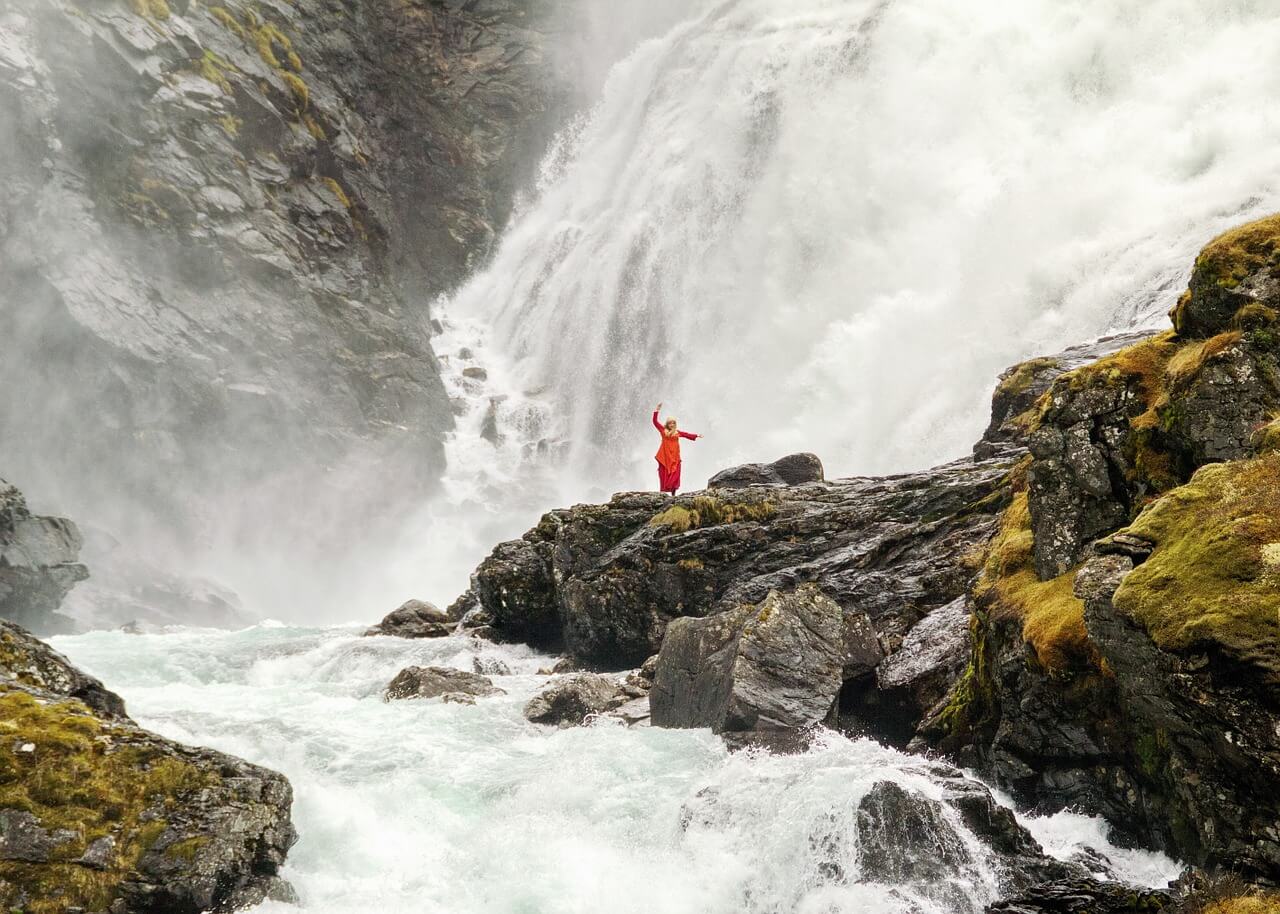 A girl in a red dress at the foot of Kjosfossen Girl on the background of Kjosfossen