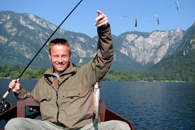 Photo of a fisherman with a caught fish in a boat on Lake Bohin Fishing on Lake Bohinj